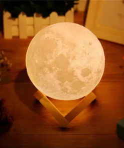 A moon lamp glowing warmly on a wooden stand, surrounded by plants and books on a wooden surface. | 28Alchemy