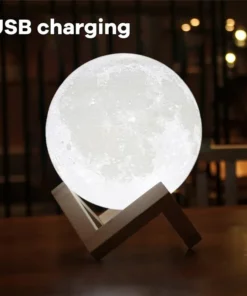 Moon-shaped lamp with wooden stand on a table, glowing softly. Text reads "USB charging" at the top-left. | 28Alchemy