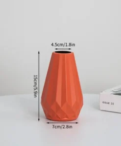 Orange geometric vase with measurements: 15cm/5.9in tall, 7cm/2.8in wide base, 4.5cm/1.8in wide top, on table near magazines. | 28Alchemy