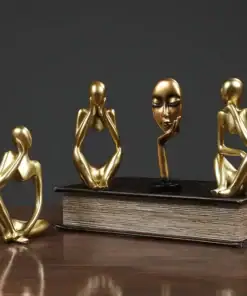 Four abstract gold figurines in thoughtful poses displayed on and beside a closed book on a wooden surface. | 28Alchemy