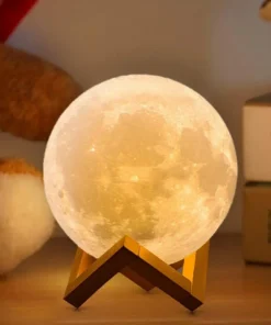 A spherical moon lamp glows warmly on a wooden stand, surrounded by a teddy bear and books on a wooden surface. | 28Alchemy
