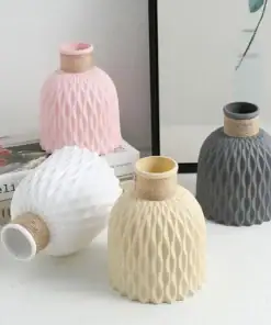 Four textured vases in pink, white, cream, and gray on a white surface with books and a framed print in the background. | 28Alchemy