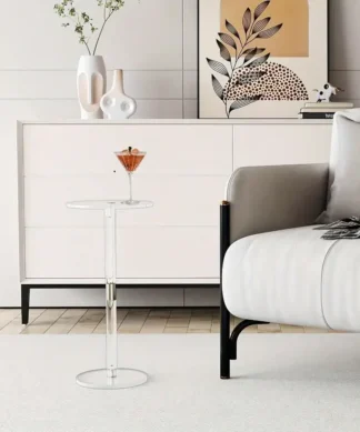 A modern living room with a white sideboard, abstract art, and a clear round side table holding a cocktail next to a sofa. | 28Alchemy