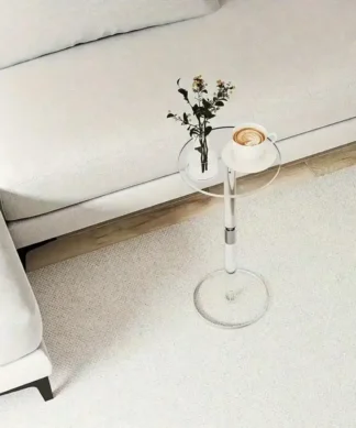 A small round side table with a vase of flowers and a pastry next to a white sofa on a light carpet. | 28Alchemy