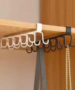 White and black metal hooks hanging from a wooden shelf, holding a belt and a necklace. | 28Alchemy