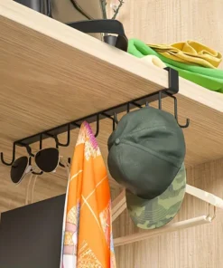 Black metal hook rack under a shelf holds sunglasses, scarf, green cap, and bag in a closet or storage space. | 28Alchemy