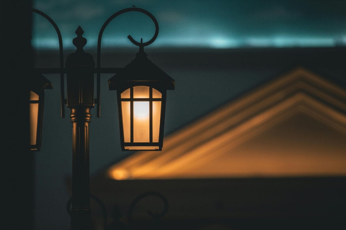 A glowing street lamp at night with a softly lit building and dark sky in the background. | 28Alchemy