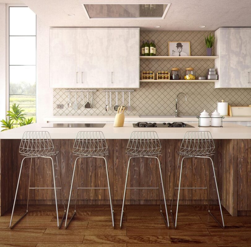 Modern kitchen with four wire barstools at a wooden island, white cabinets, and open shelves with decor and kitchenware. | 28Alchemy