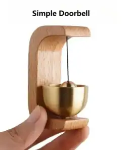A hand holds a minimalist wooden and brass doorbell with "Simple Doorbell" text above. | 28Alchemy