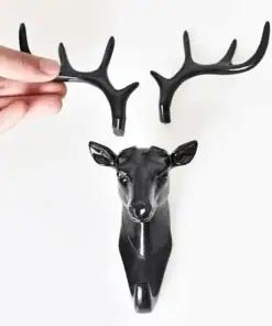 A hand attaches a black plastic antler to a matching deer head wall hook on a white background. | 28Alchemy