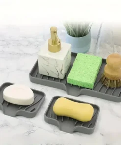 Gray soap trays holding a soap bar, a sponge, a scrub brush, and a marble-patterned dispenser on a marble countertop. | 28Alchemy