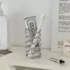A toothbrush and toothpaste tube stand upright inside a spiral metal holder on a white shelf. | 28Alchemy