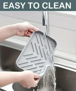 Hands rinsing a gray silicone mat under running water in a kitchen sink; "EASY TO CLEAN" text above. | 28Alchemy