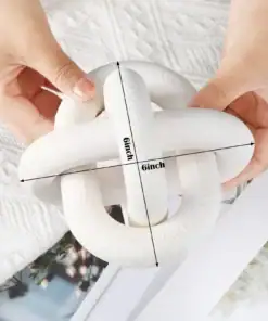 Hands holding a white wooden knot sculpture with labeled 6-inch dimensions, placed on a textured surface. | 28Alchemy