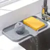 Gray sink tray holding a yellow sponge and metal scrubber, with water draining into the sink below a faucet. | 28Alchemy