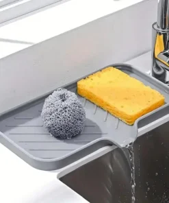 Gray sink tray holding a yellow sponge and metal scrubber, with water draining into the sink below a faucet. | 28Alchemy