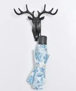 A black deer head wall hook holding a folded blue and white floral umbrella. | 28Alchemy