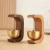 Two small desk bells with wooden frames and brass bowls, one in dark wood and one in light wood, on a wooden surface. | 28Alchemy