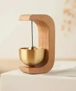 A modern wooden and brass desk bell with a curved frame, sitting on a white surface. | 28Alchemy