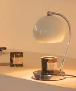 A modern desk lamp with a curved metal stand sits on a surface beside two vintage film canisters. | 28Alchemy
