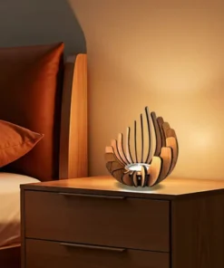 Wooden sculptural lamp emits warm light on a bedside table next to a bed with brown pillows and sheets. | 28Alchemy