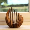 A curved wooden sculpture sits on a windowsill with a blurred green landscape outside. | 28Alchemy