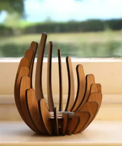 A curved wooden sculpture sits on a windowsill with a blurred green landscape outside. | 28Alchemy