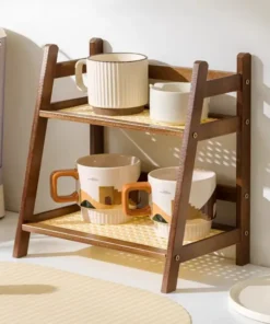 Two-tier wooden shelf holding four ceramic mugs and two small bowls, displayed on a kitchen counter in sunlight. | 28Alchemy