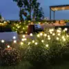 Glowing garden lights dot green bushes at night near an outdoor seating area with trees and cozy furniture. | 28Alchemy
