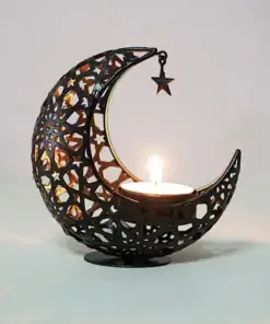 Black crescent moon candle holder with star ornament, holding a lit tealight candle, on a light surface. | 28Alchemy