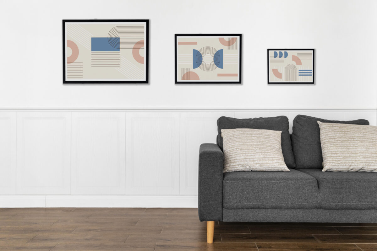 Gray sofa with beige pillows in front of a white wall with three framed abstract geometric art prints. | 28Alchemy