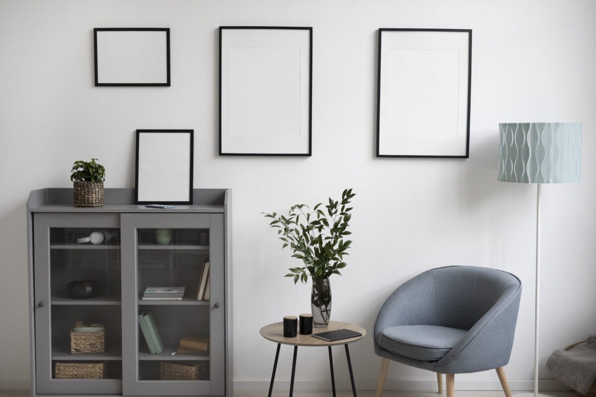 Modern living room with empty picture frames, a glass cabinet, potted plants, a blue chair, and a floor lamp. | 28Alchemy