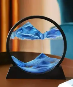A round glass sand art frame with blue and white sand forming mountain-like patterns, placed on a table. | 28Alchemy