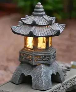 A small stone lantern with a pagoda-style roof is lit with a warm yellow light, sitting outdoors on a stone surface. | 28Alchemy