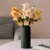 A black ribbed vase with orange and cream flowers on a light pink table, with a sofa in the background. | 28Alchemy