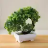 A small artificial bonsai tree with lush green leaves in a white rectangular pot on a wooden surface. | 28Alchemy