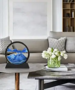 Modern living room with neutral decor, a round sand art piece, and a vase of white flowers on a coffee table. | 28Alchemy