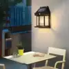 A solar wall light illuminates a patio with a table, chairs, and a potted plant at dusk. | 28Alchemy