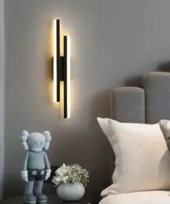 Modern wall light above a bedside table with a gray toy figure, small plant, and a bed with white bedding. | 28Alchemy