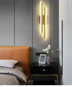 Modern bedroom with a tan headboard, black nightstand, wall-mounted light, and flowers in a vase. | 28Alchemy