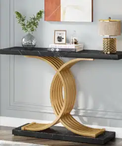 Black console table with a gold curved base, decorated with a lamp, books, a vase with greenery, and wall art above. | 28Alchemy