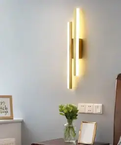 Modern vertical wall light glows beside a bed, above a vase of flowers and framed quote on a nightstand. | 28Alchemy