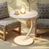 Round white table with a candle, small lamp, and vase, placed between two patterned chairs in a cozy room. | 28Alchemy