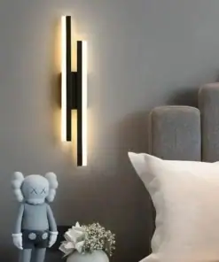Modern wall sconce emits warm light above a plush bed; a KAWS figurine and white flowers sit on the nightstand. | 28Alchemy