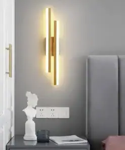 Modern vertical wall sconce with warm light above a bedside table with decor and books in a minimalistic bedroom. | 28Alchemy