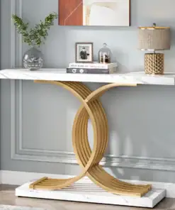 A marble console table with a gold curved base, topped with books, a vase, a lamp, and a photo frame against a gray wall. | 28Alchemy