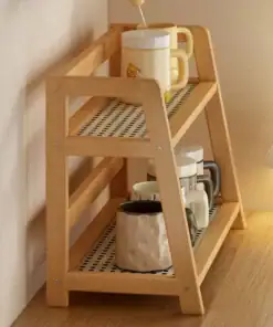 Two-tier wooden shelf holding several mugs, placed on a wooden surface near a window with blinds. | 28Alchemy