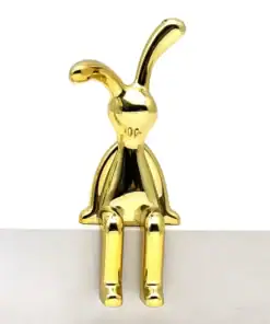 A shiny gold figurine of a bunny with long ears sits on the edge of a white surface. | 28Alchemy
