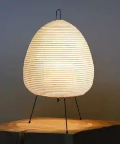A glowing paper lantern lamp with a rounded shape on three thin legs, placed on a wooden surface. | 28Alchemy