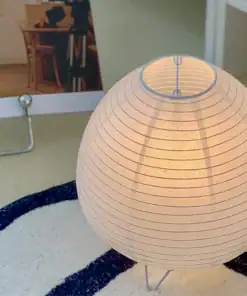 A glowing paper lantern sits on a blue and white rug, with part of a room and furniture visible in the background. | 28Alchemy